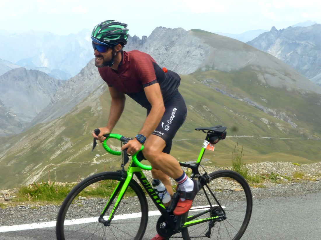 Cycliste avec vélo vert et chaussettes blanche et bleu blanc rouge vue sur la montagne